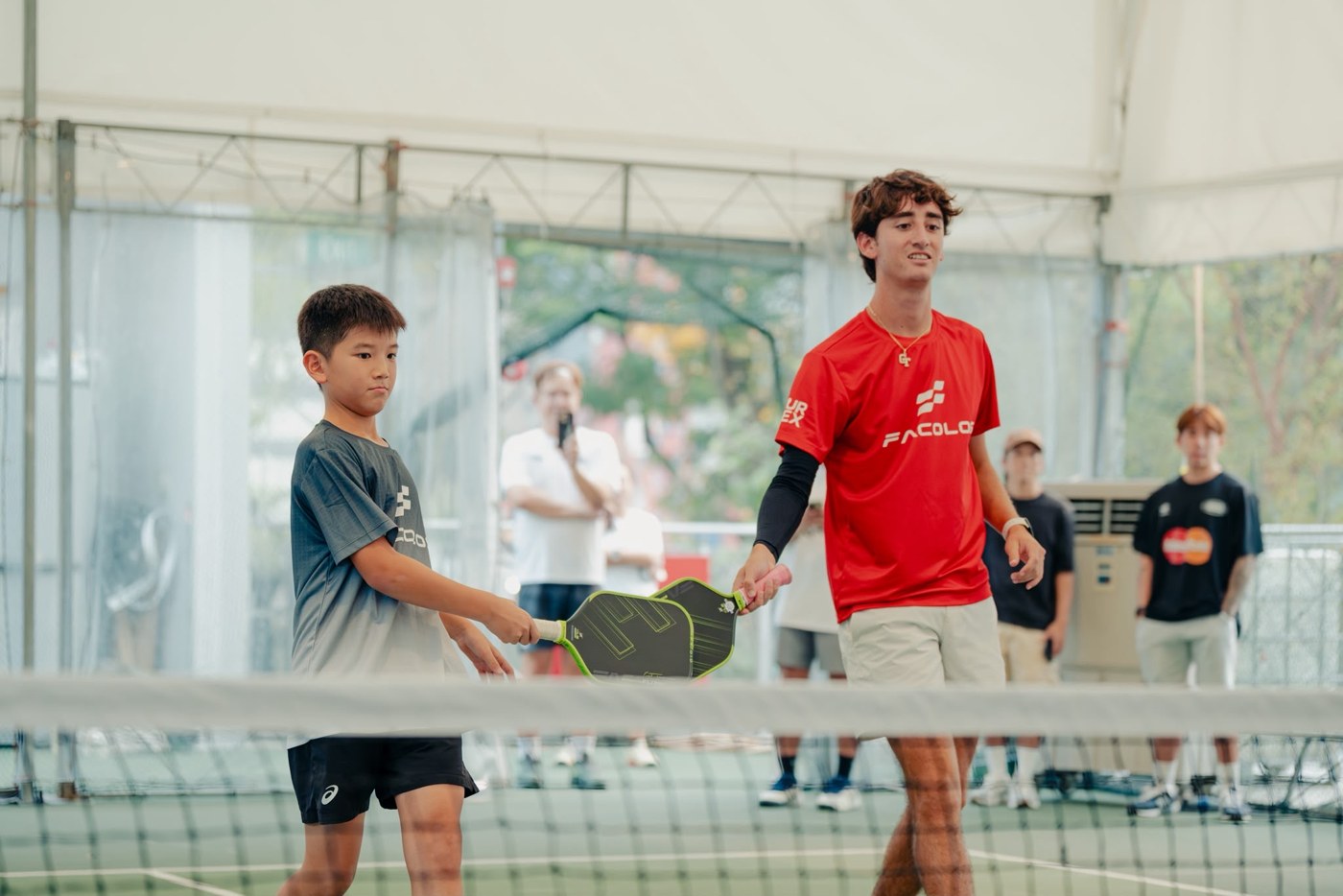 Junior player tapping paddles with his doubles partner at a match