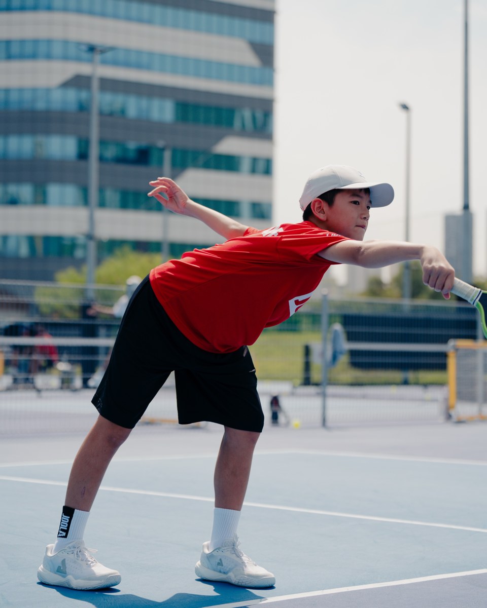 Junior player in a red shirt stretching out for a low forehand