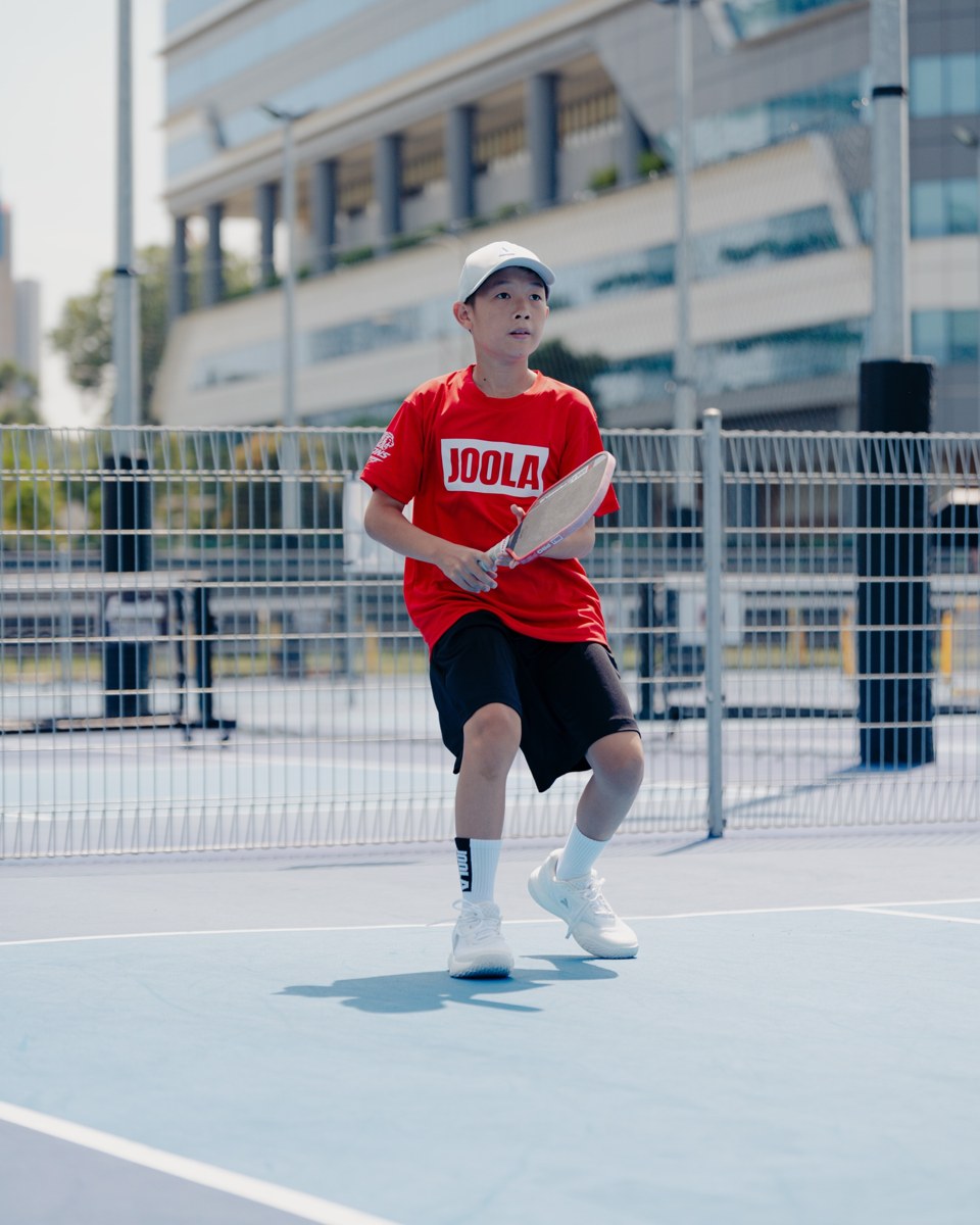 Junior player in a red shirt ready to return the ball